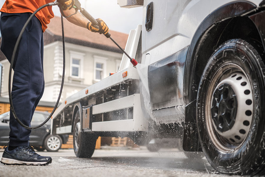 A professional power washing expert in Kansas City, MO using a commercial power washing system to clean a fleet truck.