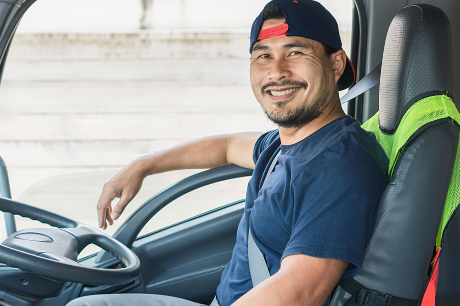 A fleet truck driver in a blue t-shirt smiling while driving a clean fleet vehicle that has been detailed by professionals in Kansas City, MO.