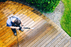 A power washing professional using soft power washing equipment to clean a wooden deck in Springfield, IL.