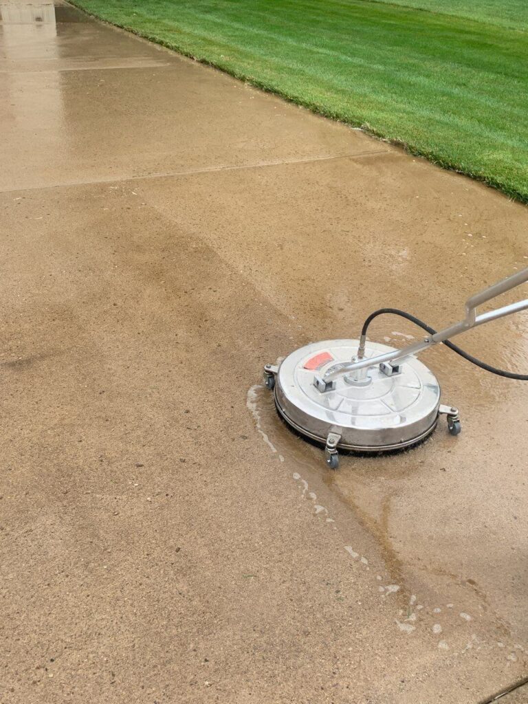 A dirty concrete driveway that is being power washed with a commercial power washer in Kansas City, MO.