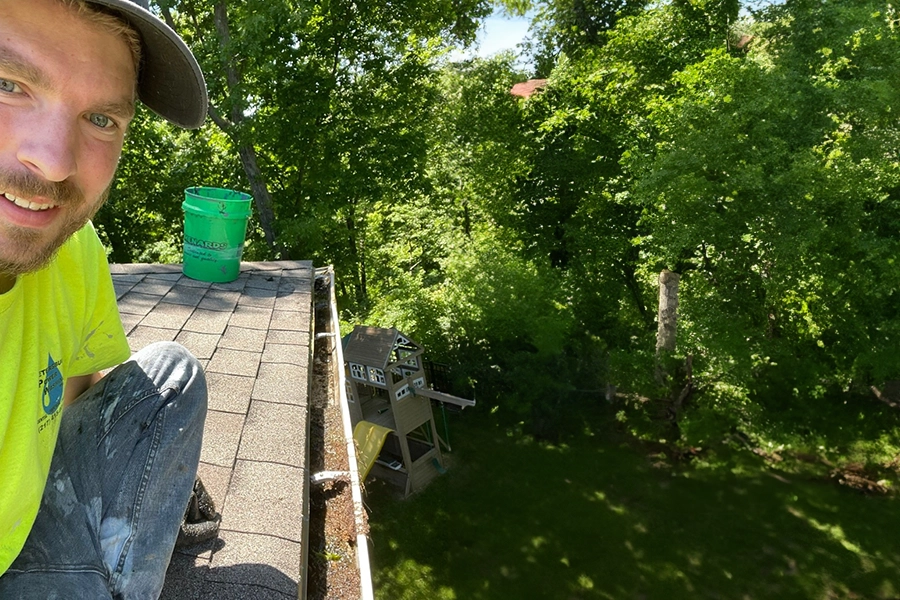 This is a photo of Robert Hillyer, owner of Royal Blue Power Washing in Kansas City, MO, cleaning gutters on a house in Parkville, MO.